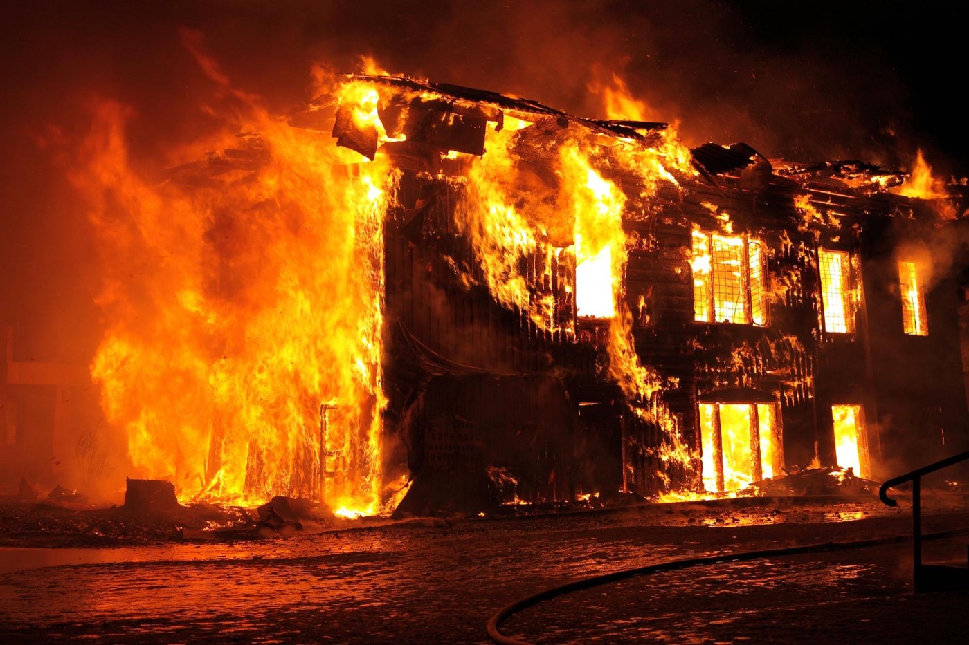 A real building fire at night, fully involved, with fire showing from every window